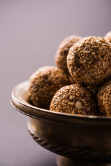 Tilgul Laddu or Til Gul balls for makar sankranti, it's a healthy food made using sesame, crushed peanuts and jaggery. served in a bowl. selective focus showing details.