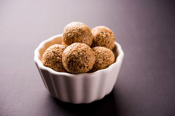 Tilgul Laddu or Til Gul balls for makar sankranti, it's a healthy food made using sesame, crushed peanuts and jaggery. served in a bowl. selective focus showing details.