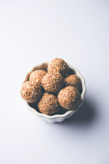 Tilgul Laddu or Til Gul balls for makar sankranti, it's a healthy food made using sesame, crushed peanuts and jaggery. served in a bowl. selective focus showing details.
