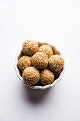 Tilgul Laddu or Til Gul balls for makar sankranti, it's a healthy food made using sesame, crushed peanuts and jaggery. served in a bowl. selective focus showing details.