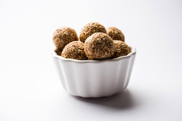 Tilgul Laddu or Til Gul balls for makar sankranti, it's a healthy food made using sesame, crushed peanuts and jaggery. served in a bowl. selective focus showing details.