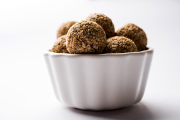 Tilgul Laddu or Til Gul balls for makar sankranti, it's a healthy food made using sesame, crushed peanuts and jaggery. served in a bowl. selective focus showing details.