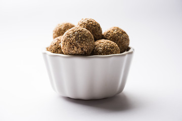 Tilgul Laddu or Til Gul balls for makar sankranti, it's a healthy food made using sesame, crushed peanuts and jaggery. served in a bowl. selective focus showing details.