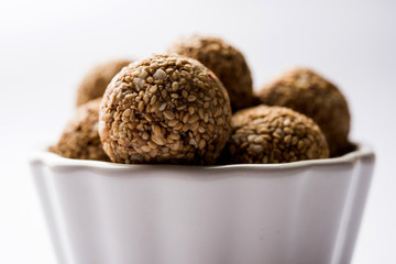 Tilgul Laddu or Til Gul balls for makar sankranti, it's a healthy food made using sesame, crushed peanuts and jaggery. served in a bowl. selective focus showing details.