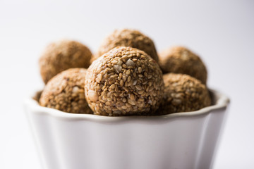 Tilgul Laddu or Til Gul balls for makar sankranti, it's a healthy food made using sesame, crushed peanuts and jaggery. served in a bowl. selective focus showing details.