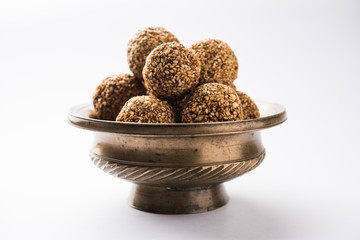 Tilgul Laddu or Til Gul balls for makar sankranti, it's a healthy food made using sesame, crushed peanuts and jaggery. served in a bowl. selective focus showing details.