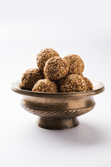 Tilgul Laddu or Til Gul balls for makar sankranti, it's a healthy food made using sesame, crushed peanuts and jaggery. served in a bowl. selective focus showing details.