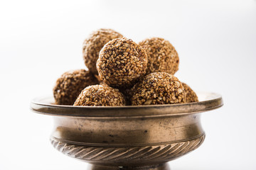 Tilgul Laddu or Til Gul balls for makar sankranti, it's a healthy food made using sesame, crushed peanuts and jaggery. served in a bowl. selective focus showing details.