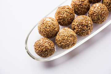 Tilgul Laddu or Til Gul balls for makar sankranti, it's a healthy food made using sesame, crushed peanuts and jaggery. served in a bowl. selective focus showing details.