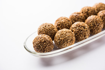 Tilgul Laddu or Til Gul balls for makar sankranti, it's a healthy food made using sesame, crushed peanuts and jaggery. served in a bowl. selective focus showing details.