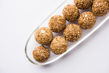 Tilgul Laddu or Til Gul balls for makar sankranti, it's a healthy food made using sesame, crushed peanuts and jaggery. served in a bowl. selective focus showing details.
