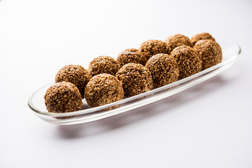 Tilgul Laddu or Til Gul balls for makar sankranti, it's a healthy food made using sesame, crushed peanuts and jaggery. served in a bowl. selective focus showing details.