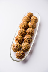 Tilgul Laddu or Til Gul balls for makar sankranti, it's a healthy food made using sesame, crushed peanuts and jaggery. served in a bowl. selective focus showing details.