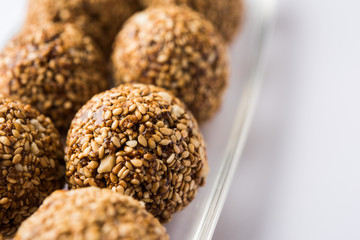 Tilgul Laddu or Til Gul balls for makar sankranti, it's a healthy food made using sesame, crushed peanuts and jaggery. served in a bowl. selective focus showing details.