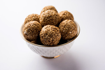 Tilgul Laddu or Til Gul balls for makar sankranti, it's a healthy food made using sesame, crushed peanuts and jaggery. served in a bowl. selective focus showing details.