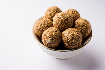 Tilgul Laddu or Til Gul balls for makar sankranti, it's a healthy food made using sesame, crushed peanuts and jaggery. served in a bowl. selective focus showing details.