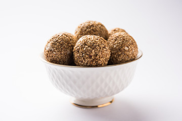 Tilgul Laddu or Til Gul balls for makar sankranti, it's a healthy food made using sesame, crushed peanuts and jaggery. served in a bowl. selective focus showing details.
