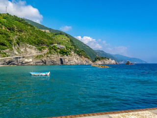 Sea view with a boat, cliffs and mountain hills, bay of Monterosso at Monterosso al Mare, Cinque Terre, Italy