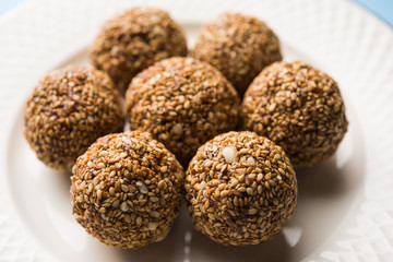 Tilgul Laddu or Til Gul balls for makar sankranti, it's a healthy food made using sesame, crushed peanuts and jaggery. served in a bowl. selective focus showing details.