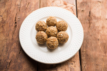 Tilgul Laddu or Til Gul balls for makar sankranti, it's a healthy food made using sesame, crushed peanuts and jaggery. served in a bowl. selective focus showing details.