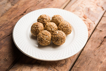 Tilgul Laddu or Til Gul balls for makar sankranti, it's a healthy food made using sesame, crushed peanuts and jaggery. served in a bowl. selective focus showing details.