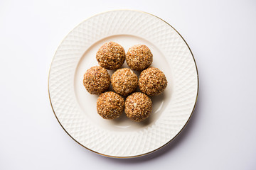 Tilgul Laddu or Til Gul balls for makar sankranti, it's a healthy food made using sesame, crushed peanuts and jaggery. served in a bowl. selective focus showing details.