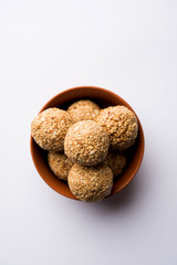 Tilgul Laddu or Til Gul balls for makar sankranti, it's a healthy food made using sesame, crushed peanuts and jaggery. served in a bowl. selective focus showing details.
