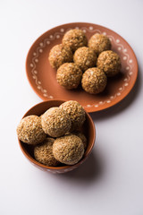 Tilgul Laddu or Til Gul balls for makar sankranti, it's a healthy food made using sesame, crushed peanuts and jaggery. served in a bowl. selective focus showing details.