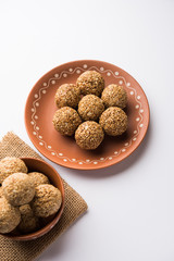 Tilgul Laddu or Til Gul balls for makar sankranti, it's a healthy food made using sesame, crushed peanuts and jaggery. served in a bowl. selective focus showing details.