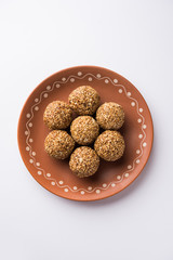Tilgul Laddu or Til Gul balls for makar sankranti, it's a healthy food made using sesame, crushed peanuts and jaggery. served in a bowl. selective focus showing details.