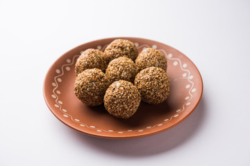 Tilgul Laddu or Til Gul balls for makar sankranti, it's a healthy food made using sesame, crushed peanuts and jaggery. served in a bowl. selective focus showing details.