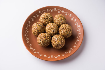 Tilgul Laddu or Til Gul balls for makar sankranti, it's a healthy food made using sesame, crushed peanuts and jaggery. served in a bowl. selective focus showing details.