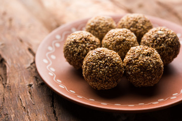 Tilgul Laddu or Til Gul balls for makar sankranti, it's a healthy food made using sesame, crushed peanuts and jaggery. served in a bowl. selective focus showing details.