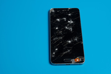 Cell phone with broken screen on a blue background.