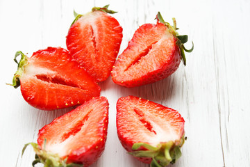 Sliced strawberries on white wooden background. Berry background with place for text. Selective focus.