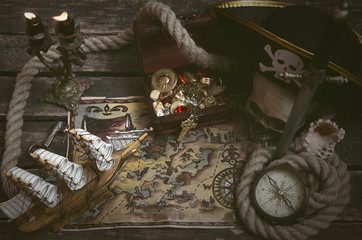 Pirate ship, treasure map, treasure chest full of gold and a compass on a wooden captain table...