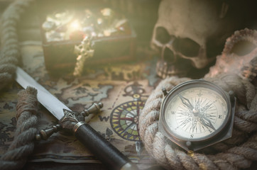 Pirate treasure map, treasure chest full of gold, compass, mooring rope and a sword on a wooden...