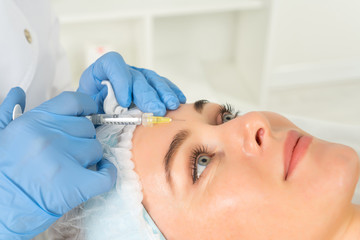 The doctor cosmetologist makes the Rejuvenating facial injections procedure for tightening and smoothing wrinkles on the face skin of a women in a beauty salon.Cosmetology skin care.