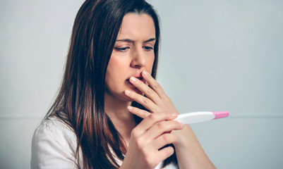 Worried pregnant woman looking at a pregnancy test