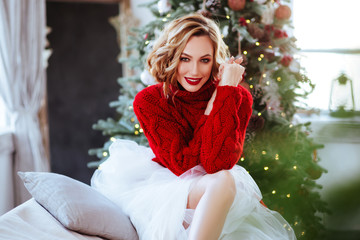 holidays, celebration and people concept - smiling woman in red sweater over christmas tree background