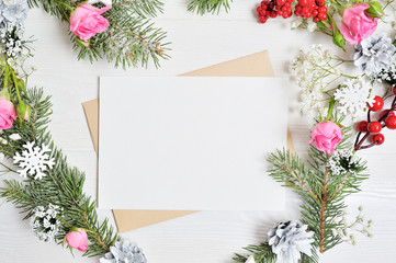 Mockup of Christmas Wreath in form of heart with sheet of paper Decorated with white snowflakes and cones. White wooden background with place for your text