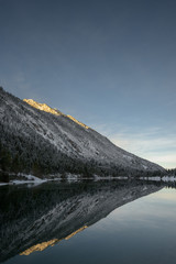 reflection of snowy mountains in winter lake plansee in tirol