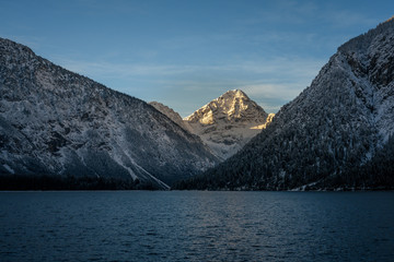 lighted snowy mountain thaneller with lake plansee at winter