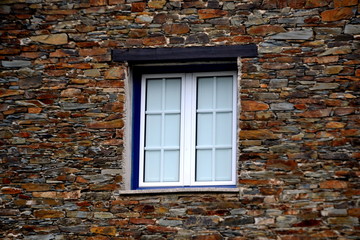 Rustic hand-hewn wood window set into a stone wall built from schist in Piodão, made of shale rocks stack, one of Portugal's schist villages in the Aldeias do Xisto.