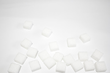 Few spread sugar cubes from the down side of the image to the top on white background