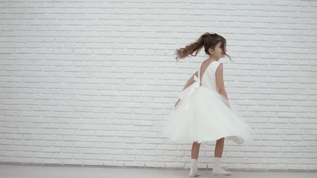 beautiful girl dancing in a chic white dress. The girl is spinning, her dress is developing from the movement. Beautiful video of a little bridesmaid at a wedding