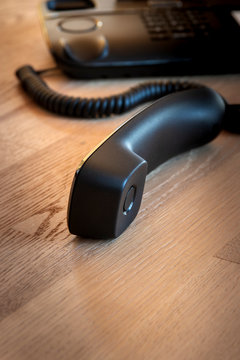 Black office phone and handset on wooden table