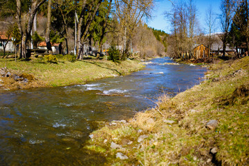 Fototapeta na wymiar Spring stream flowing along rural area. Mountain region