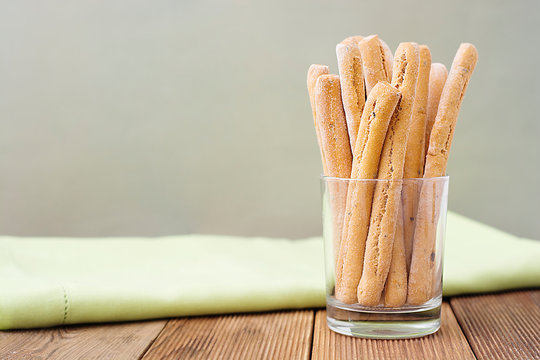 Grissini on wooden table. Traditional italian snack with herbs. Copy space.