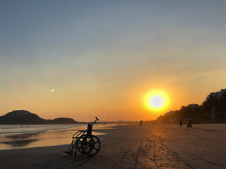Fototapeta premium Wheelchair at the beach during sunset